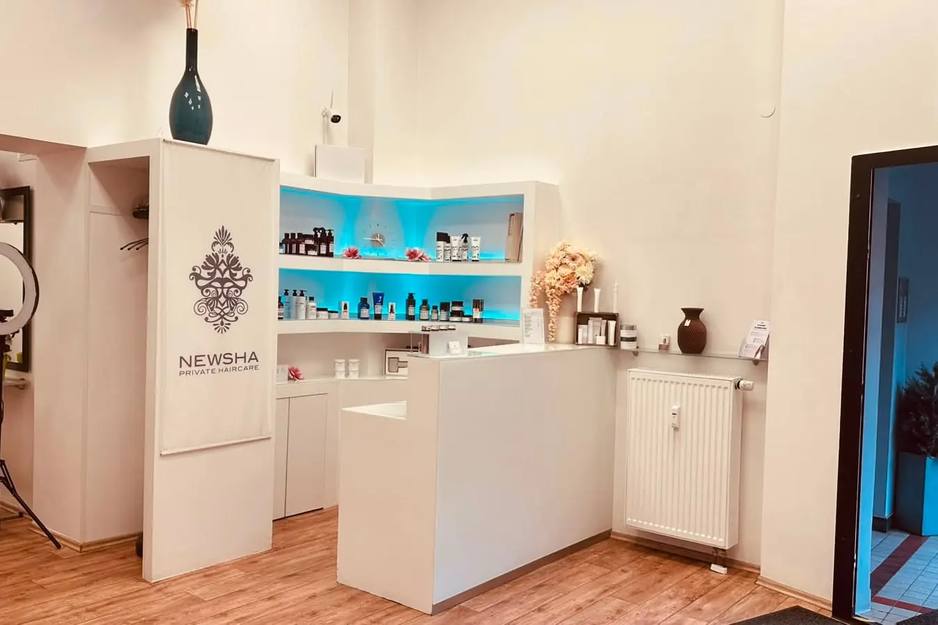 Empfang des Salons Comhair mit weißer Theke und beleuchtetem Pflegeregal